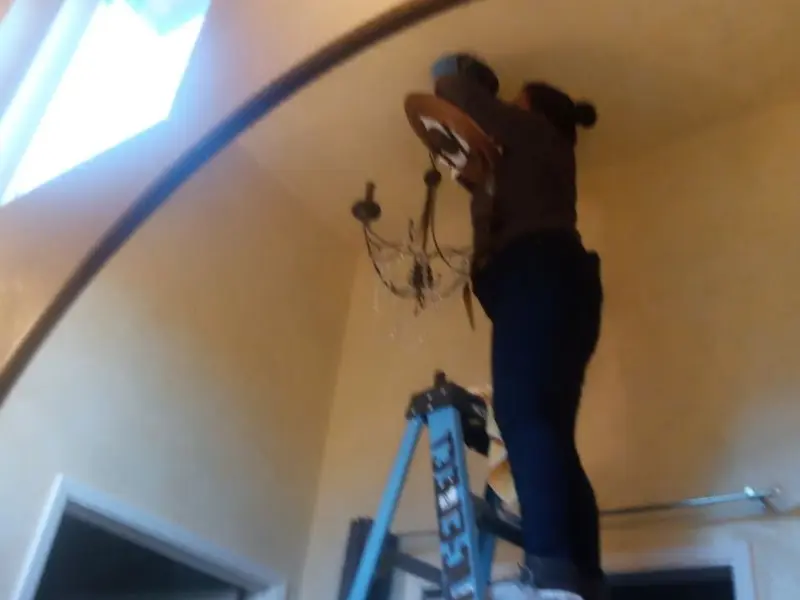 Electrician installing a chandelier in a Charlotte residence